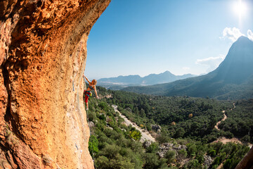 Wall Mural - Girl climbs on the rock, rock climbing in Turkey, the sports girl is engaged in rock climbing.