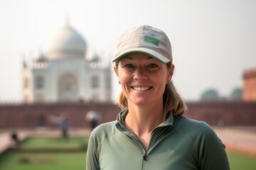 Poster - Environmental portrait photography of a merry girl in her 40s wearing a casual baseball cap in front of the taj mahal in agra india. With generative AI technology