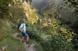 © Guzel - A gray-haired man with backpack and sticks stands on a trail over a beautiful view of a sunlit mountain valley, Austria