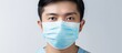 Close up portrait of Asian man wearing blue surgical face mask isolated on white background refusing coronavirus infection