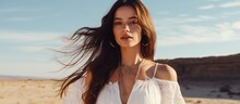 Copy space available for a stunning dark haired girl in a white dress adorned with boho jewelry posing in a sandy valley with a blue sky Beauty Fashion and Boho style