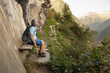© Guzel - Gray-haired athletic man sitting on a wooden bench under a rock on a hiking mountain trail