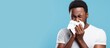 © vxnaghiyev - African American man sick sneezes shows cold symptoms white t shirt blue background copy space