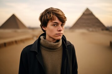 Poster - Photography in the style of pensive portraiture of a cheerful boy in his 30s wearing a dramatic choker necklace at the pyramids of giza egypt. With generative AI technology