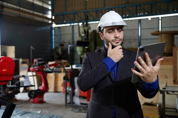 Wall Mural - businessman using tablet for video call online and talking to someone in robot factory