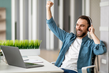 Aufkleber - Cheerful young office employee in headphones listening to music at workplace