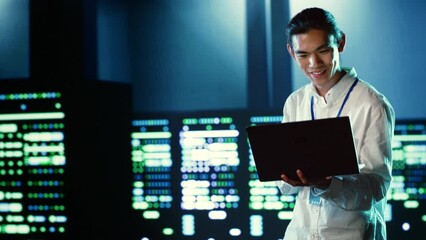 Poster - Skillful employee wandering around data center infrastructure providing processing resources for different workloads. Asian admin doing checkup on servers tasked with solving computational operations