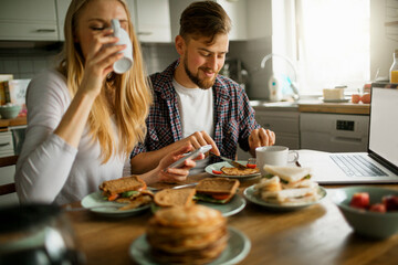 Young couple having breakfast and drinking coffee in the kitchen