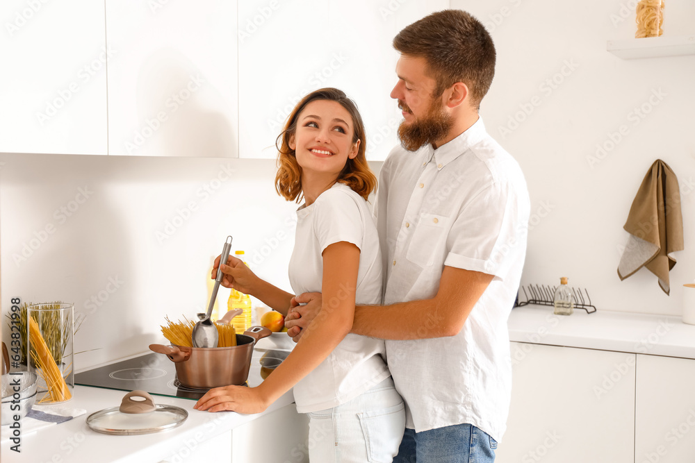 Happy couple in love boiling pasta in kitchen
