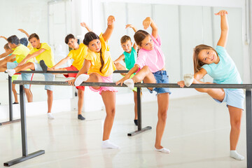 Group of children doing leg stretch at the ballet barre