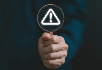 Wall Mural - businessman using laptop showing warning triangle and exclamation sign icon warning of dangerous pro