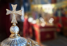 Christian Cross In Front Of The Blurred Church Background, Blurred Bokeh Lighting From The Candles, Copy Space