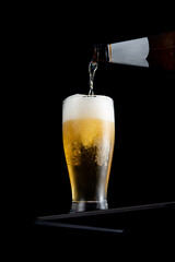 Wall Mural - Fresh cold beer in a glass on table on black background.