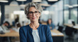 © GustavsMD - Successful entrepreneur in office with team at back. Senior business woman standing in an office