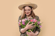 © New Africa - Happy young woman in straw hat holding bouquet of beautiful tulips on beige background