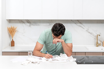 Wall Mural - Close up of unhappy man sitting at the table, stressed and confused by calculate expense from invoice or bills, have no money to pay mortgage or loan. High prices and spending money concept