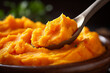Close-up of a spoonful of mashed carrots highlighting the smoothness and vibrant color of early stage baby food 