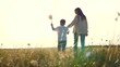 serene setting park sunset mother lovingly clasps son hand. joyful family, strolling together children summery park. cherished moment evoking dreams childhood. windmill spins small child hand against