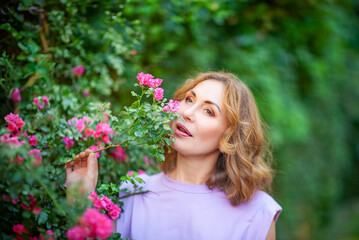 Wall Mural - Beautiful successful middle aged woman smelling bloom roses and enjoying in garden outdoors.