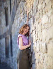 Wall Mural - Beautiful successful middle aged woman posing against a stone wall street, photo shoot