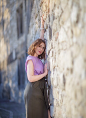 Wall Mural - Beautiful successful middle aged woman posing against a stone wall street, photo shoot