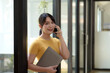 © amnaj - Casual City Lifestyle. Happy Asian woman talking on mobile phone a in modern office.