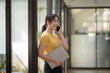 © amnaj - Casual City Lifestyle. Happy Asian woman talking on mobile phone a in modern office.