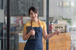 © amnaj - Beautiful business owner standing in front of the doorway preparing to take orders from customers.