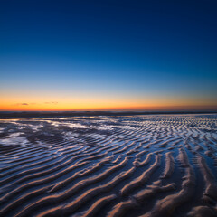 Wall Mural - a seascape during sunset. lines of sand on the seashore. bright sky during sunset. a sandy beach at 
