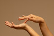 © wavebreak3 - Touching hands of biracial woman on brown background with copy space