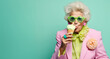 © Santijago - Old senior charming lady in pastel color clothes eat an ice cream on cone. Funny melting scene with food an older aged woman. The background is mint green, copy space.