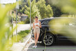 © 24K-Production - Attractive woman charging an EV car in an electric vehicle parking lot. Concept of city life and traffic.