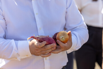 A man in a white shirt holds a bow. Close-up of male hands holding a bow. A man without a face, holding a bow in his hands.