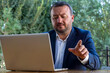 © oybekostanov - a man pointing, mature business man in an outdoor ambition working in laptop ,blue coat suit,multiracial asian, successful businessman.