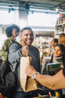 © Maskot - Smiling male customer taking shopping bag from clerk at checkout in convenience store