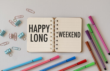 Business concept. On the table are pencils, paper clips, paper with the inscription - Happy Long Weekend