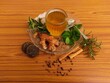 © Daney - A cup of herbal tea on wooden table with ingredients. Herbal tea, medicinal tea, healthy tea, made from Ginger, mint, tulsi, cinnamon, peppercorns, rosemary, jaggery.