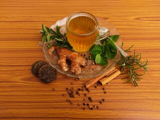 A cup of herbal tea on wooden table with ingredients. Herbal tea, medicinal tea, healthy tea, made from Ginger, mint, tulsi, cinnamon, peppercorns, rosemary, jaggery.