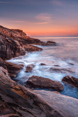 Sunrise long exposure of the sea on the rocks in front of Castello Boccale, Livorno, Tuscany 