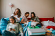 © Maskot - Happy female friends using smart phones in living room at home