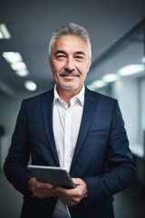 Canvas Print - portrait of a happy mature businessman holding a tablet while standing in an office