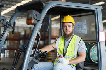 Male warehouse worker driving and operating on forklift truck for transfer products or parcel goods in the industrial storage factory warehouse