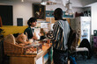 © Maskot - Female entrepreneur talking with customer at checkout counter in food store