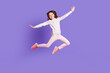 © deagreez - Full length photo of carefree pretty little girl dressed dotted pullover arms sides jumping high isolated purple color background