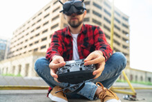 Outdoor Portrait Of Casually Dressed Male Fpv Pilot Operating Multicopter Drone Using Goggles Nad Remote Controller