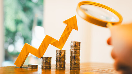 Up Arrow symbol and coins stack with magnifying glass. Concepts of the banking system, rising interest rates, inflation, and savings.