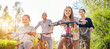 © Soloviova Liudmyla - Smiling father and mother with two daughters during summer outdoor bicycle riding. They enjoy togetherness in the summer city park. Happy parenthood and childhood or active sport life concept image.