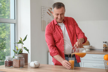 Sticker - Mature man pouring orange juice into glass in kitchen