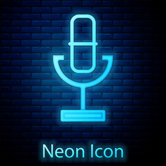 Sticker - Glowing neon Microphone icon isolated on brick wall background. On air radio mic microphone. Speaker sign. Vector