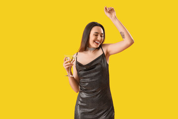 Wall Mural - Beautiful woman with martini dancing on yellow background